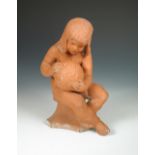 An Arts & Crafts Bromsgrove School style terracotta figure, modelled as a young girl sitting on a