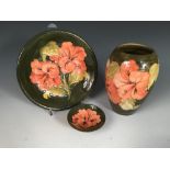 A small collection of Moorcroft Hibiscus pattern wares, comprising a vase, plate and pin dish, all