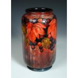 A large Moorcroft leaves and fruit pattern flambé vase, the cylindrical form decorated over a red