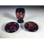 Two small Moorcroft Pomegranate pattern bowls, each decorated to a deep blue ground, together with a