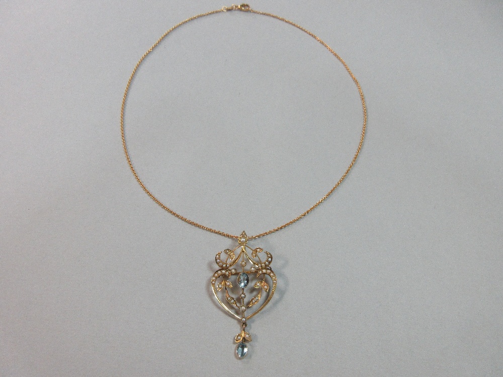 An Edwardian aquamarine and seed pearl pendant / brooch on an 18ct gold chain, of light, pierced and