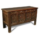 An oak panelled coffer, late 17th century, with a plank top, foliate carved decoration, on long