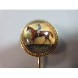 A reverse carved and painted crystal stick pin depicting a race horse with jockey up, the chestnut