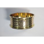 A yellow metal napkin ring, stamped 9ct, circular with engine turned decoration, engraved 'F' in