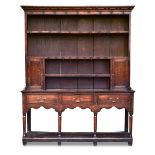 An oak boarded dresser, 18th century, with boarded plate rack, iron hooks and spice cupboards