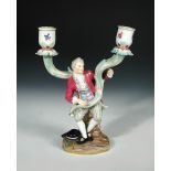 A Meissen two-branch candelabrum, circa 1900, modelled as an 18th century gentleman seated on