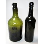 A green glass jeroboam bottle with stamped initials and another bottle, both rims trailed above