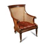 A Regency mahogany framed library bergere, with scroll carved arms, buttoned leather seat cushion