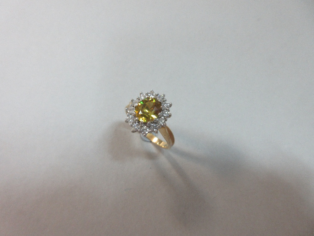 A golden sphene and diamond cluster ring set in 18ct gold, the oval cut sphene of intense slightly