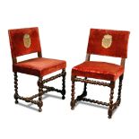 A matched pair of Spanish walnut chairs, 17th century, the red upholstery embroidered with applied