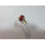 A ruby and diamond cluster ring, the oval cut ruby in a border of fifteen rose cut diamonds to X-