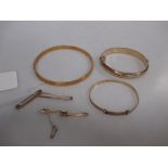 Three 9ct marked bangles, two 9ct pin clips, also a 15ct two stone bar brooch, together 34g