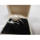 A pearl and diamond ring, the 7mm pearl set to either side with two small round diamonds, all set in