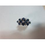 A contemporary sapphire and diamond ring, designed as a tiered chequerboard of round cut sapphires