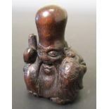 A 19th century wood netsuke carved as Fukurokuju seated laughing holding a scroll in his right