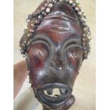 A hardwood dance mask, Dan people, Liberia, mounted with plant fibre, fabric and cowrie shells, 46cm
