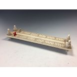 A 19th century carved ivory cribbage board, on turned supports with red stained and white pegs