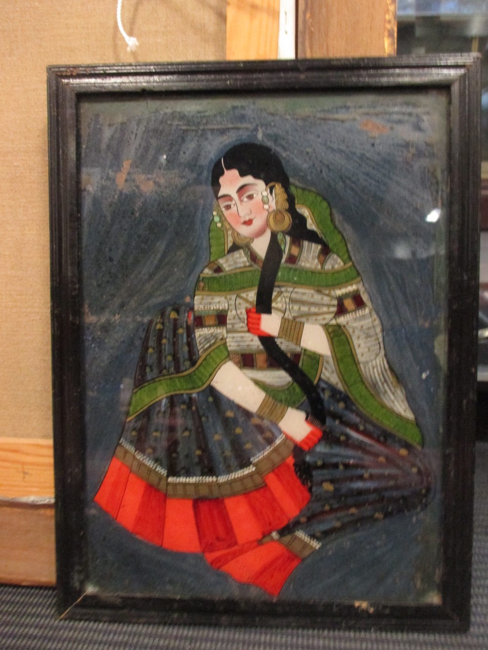 Rajasthan painting on reverse glass of a seated lady in local dress, 35 x 25 cm