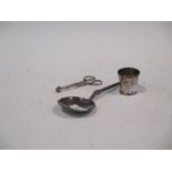 A silver serving spoon, scissor action sugar nips and a spirit tumbler