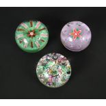 Two Paul Ysart floral paperweights, one to a purple ground with bubble surround, the other with