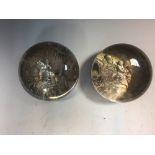 Two 19th century pinchbeck glass paperweights, each with silver metal scenes in relief, one