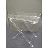 A clear lucite butler's tray and stand, the tray with pierced handles to either end 79 x 76.50 x