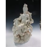 A blanc de Chine figure of Guanyin enthroned on a lotus leaf borne by waves, jewels in her hair