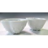 A pair of Seto white glazed sake bowls, the cinquefoil rims above prunus sprays moulded on the