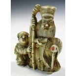A late 19th/early 20th century ivory netsuke carved as Jurojin standing with a boy attendant by a