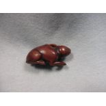 An 18th century wooden netsuke carved as a hare, the animal carved in reclining position, the