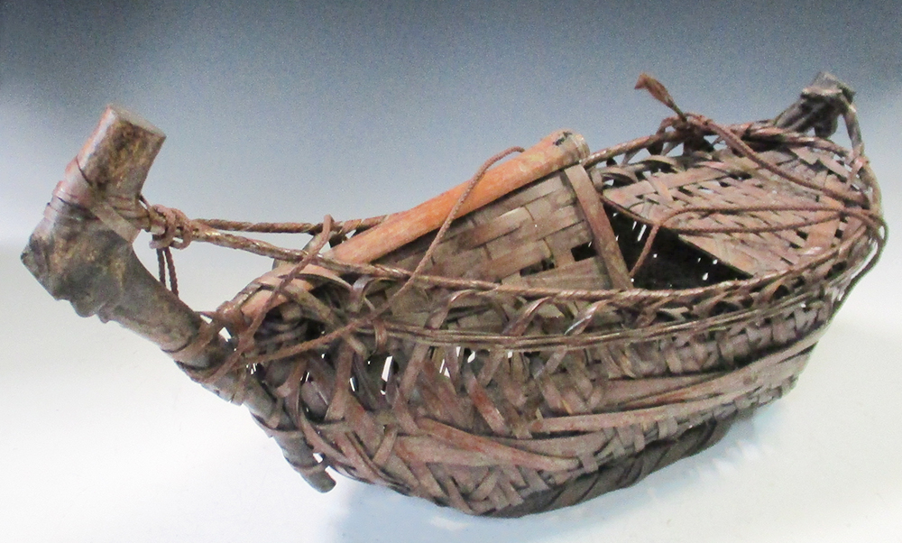 A bamboo basket work ikebana ship, the rustic boom raised before a canopy over the bow, the seat