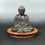 A 19th century bronze Buddha with wood stand, modelled on the Daibutsu at Kotokin Temple,