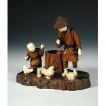 A late 19th/early 20th century wood and ivory group, the father and child standing over their