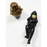 A Kobe Daruma toy and a lion masked man netsuke, the first depicting the monk wrapped in his