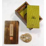 A wooden boxed Han dynasty jade dragon bi, the green stone with a dusting of brown, one side
