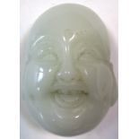 A pale nephrite jade Budai mask toggle, a third eye carved centrally to his forehead as he laughs,