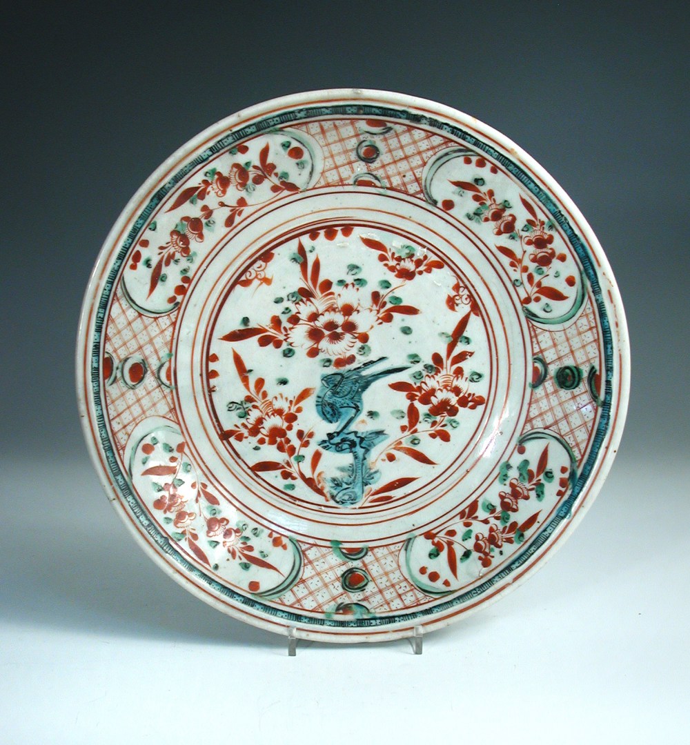 A 17th century Swatow polychrome dish, the central green bird perched on a rock by three red