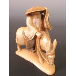 An early 20th century ivory figure of Fukurokuju riding a donkey with one hand on his straw hat