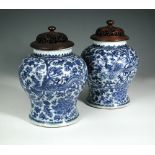 A pair of blue and white jars, period of Kangxi, with pierced wood covers, the baluster bodies