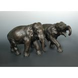 A pair of early 20th century bronze elephants, both pachyderms walking, the smaller bellowing as she