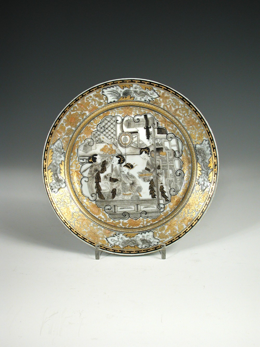 A gilt and grisaille plate in the 'Jesuit' style, centrally painted with three ladies and a