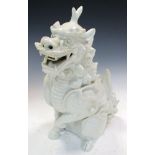 A 19th century white glazed figure of a seated qilin, its mouth opened in a mischievous grin, one