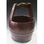 An early 20th century coopered hardwood water bucket, the handle raised above the barrel shaped