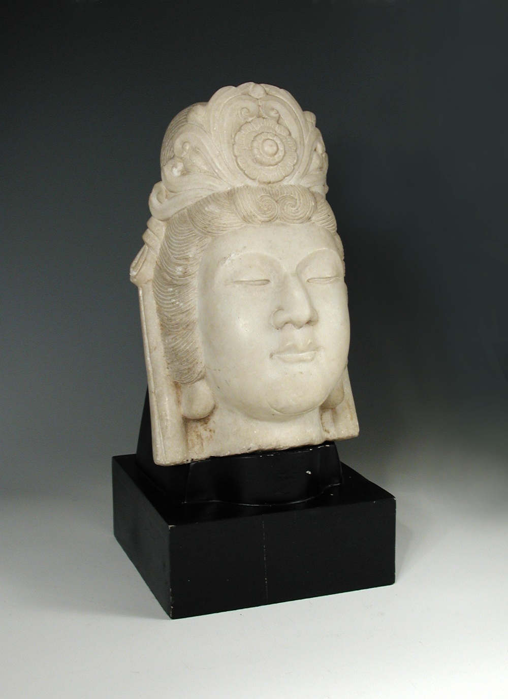 A late 19th/early 20th century white marble head of Guanyin, her headdress centred by a rosette