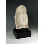 A late 19th/early 20th century white marble head of Guanyin, her headdress centred by a rosette