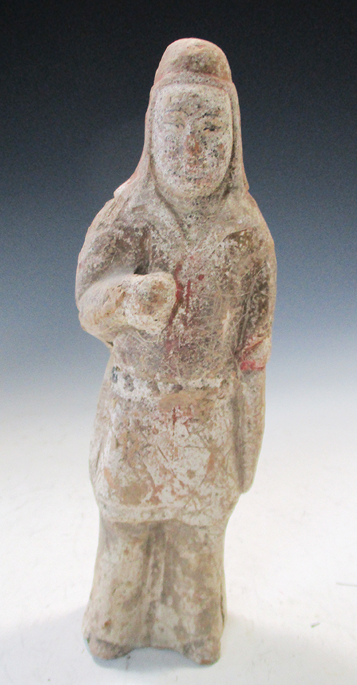 A Tang dynasty pottery standing figure, he stands wearing a red hood above a dark jacket, his left