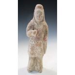 A Tang dynasty pottery standing figure, he stands wearing a red hood above a dark jacket, his left