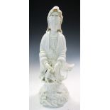 A blanc de Chine figure of Guanyin standing pointing down to the fish within her basket as she