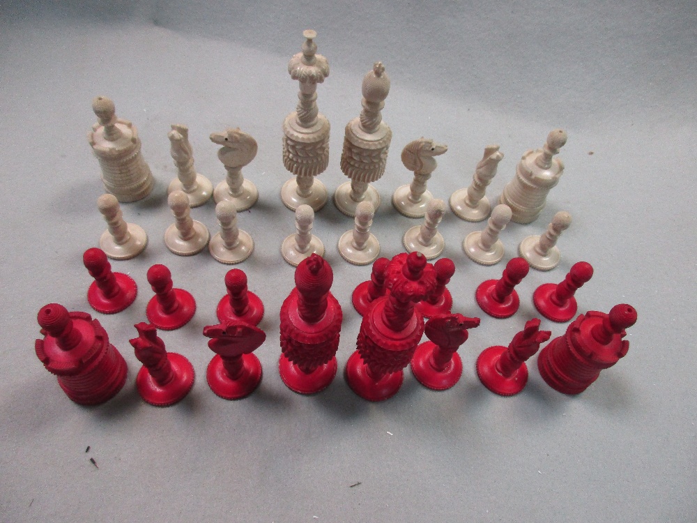 A 19th century red and white bone chess set, each piece ring turned with gadroons and flutes, the