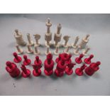 A 19th century red and white bone chess set, each piece ring turned with gadroons and flutes, the